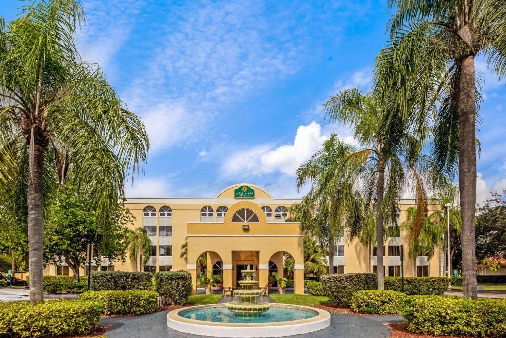 迈阿密湖迈阿密湖拉金塔旅馆及套房的一座黄色的大建筑,前面有一个喷泉