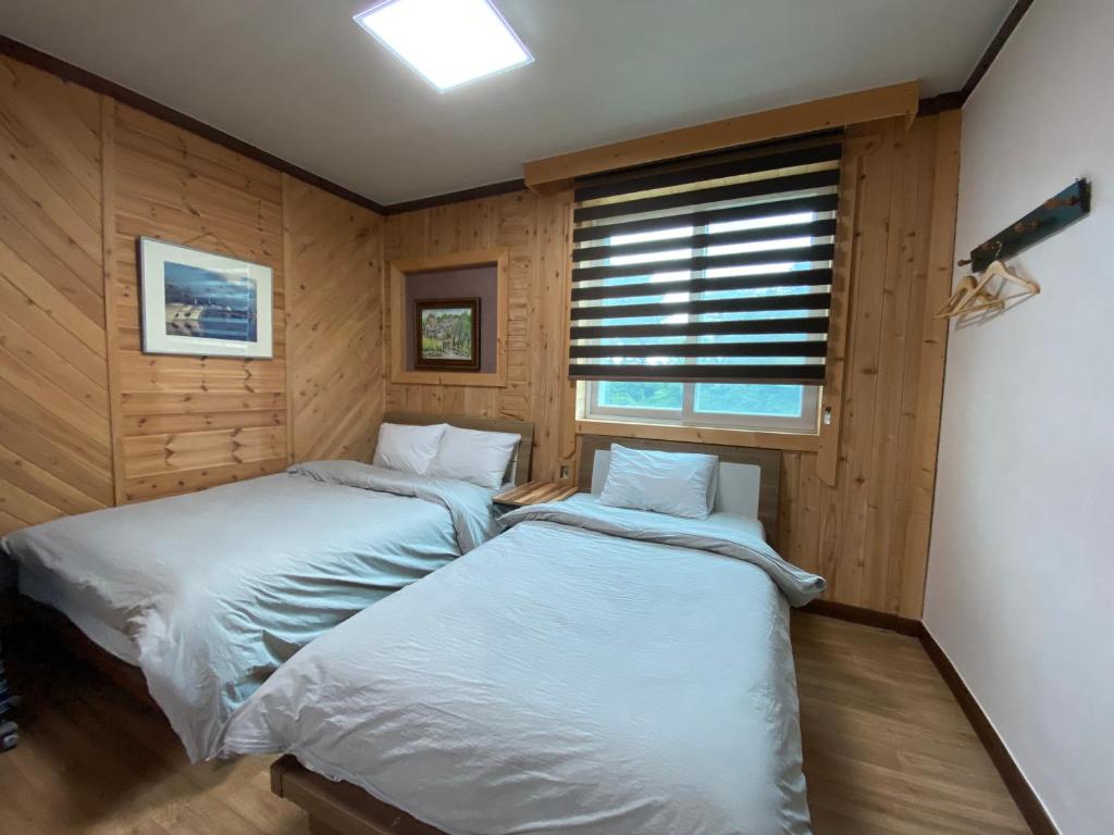 束草市Smile Resort的配有木墙和窗户的客房内的两张床