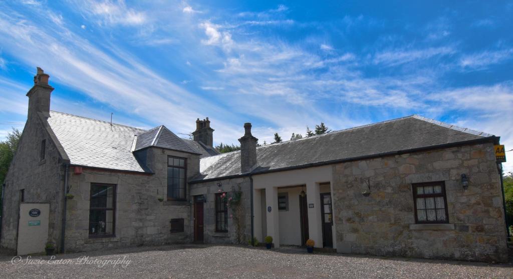 邓弗姆林Clarke Cottage Guest House的一座蓝色天空的古老石头建筑