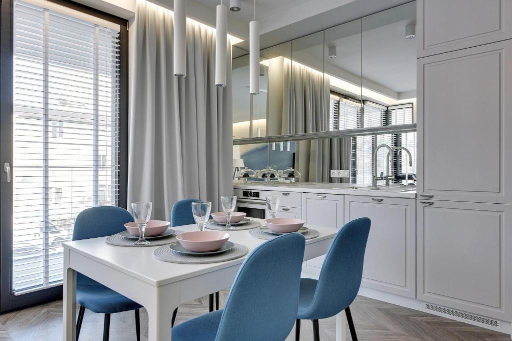 索波特Grand Apartments - Indygo Okrzei Residence Sopot的一间配备有白色桌子和蓝色椅子的用餐室
