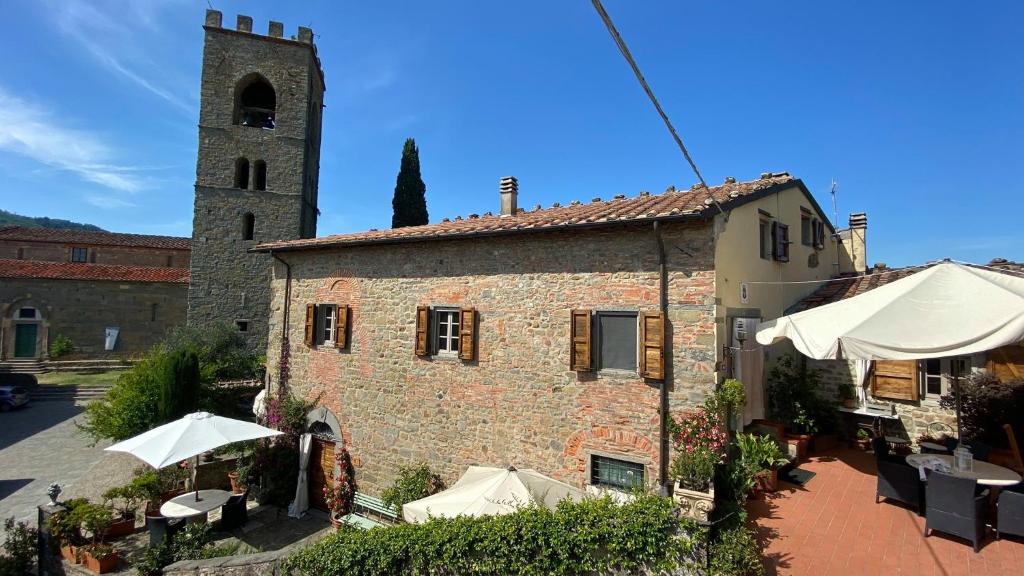 博尔格阿布贾诺La Magione dei Todaro的一座配有桌子和遮阳伞的建筑和一座塔楼