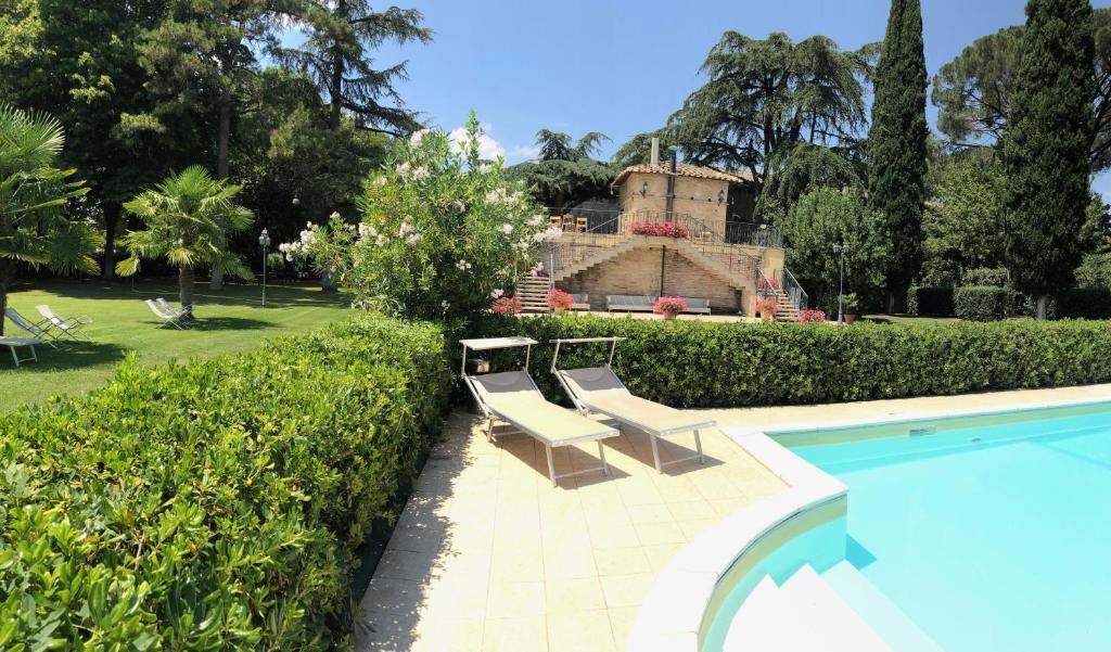 PetrignanoHotel Assisi Parco Dei Cavalieri的一座房子旁带两把椅子的游泳池