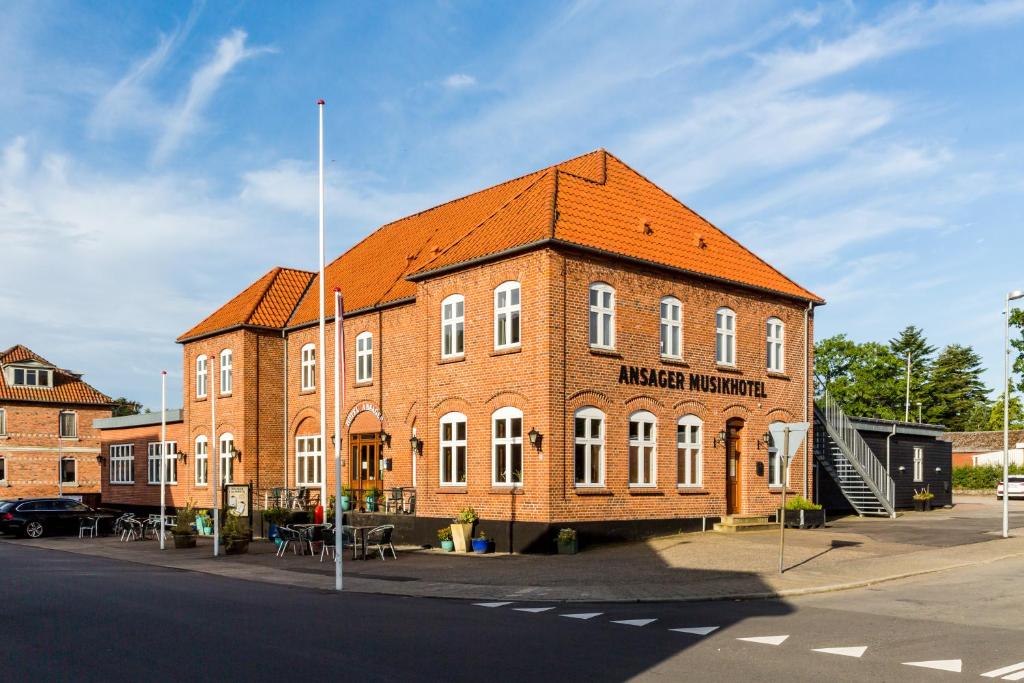 安斯艾厄Ansager Hotel og Hytteby的一座大型砖砌建筑,屋顶橙色