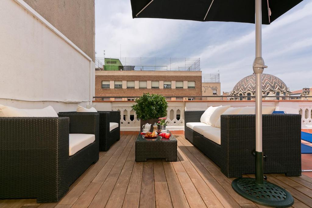 巴塞罗那BCN帕斯德格拉齐亚鲁卡莫拉公寓的一个带沙发和遮阳伞的屋顶庭院