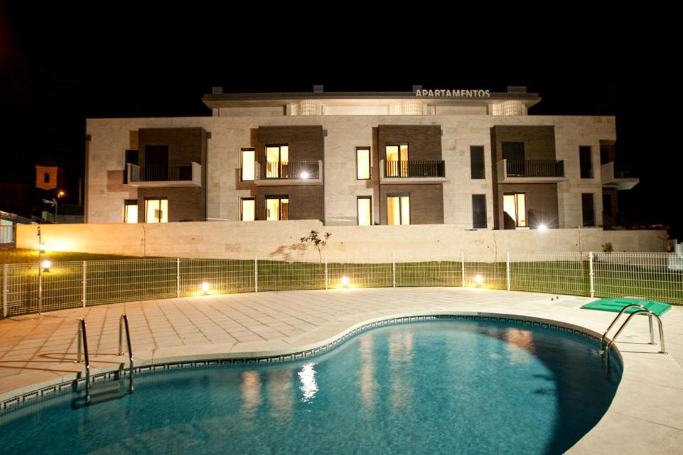 索托德拉马里纳破碎海岸公寓酒店的一座游泳池,在晚上在建筑物前