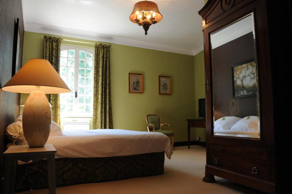 Bruniquel阿韦龙峡谷餐厅旅馆的一间卧室配有一张床、一盏灯和一面镜子