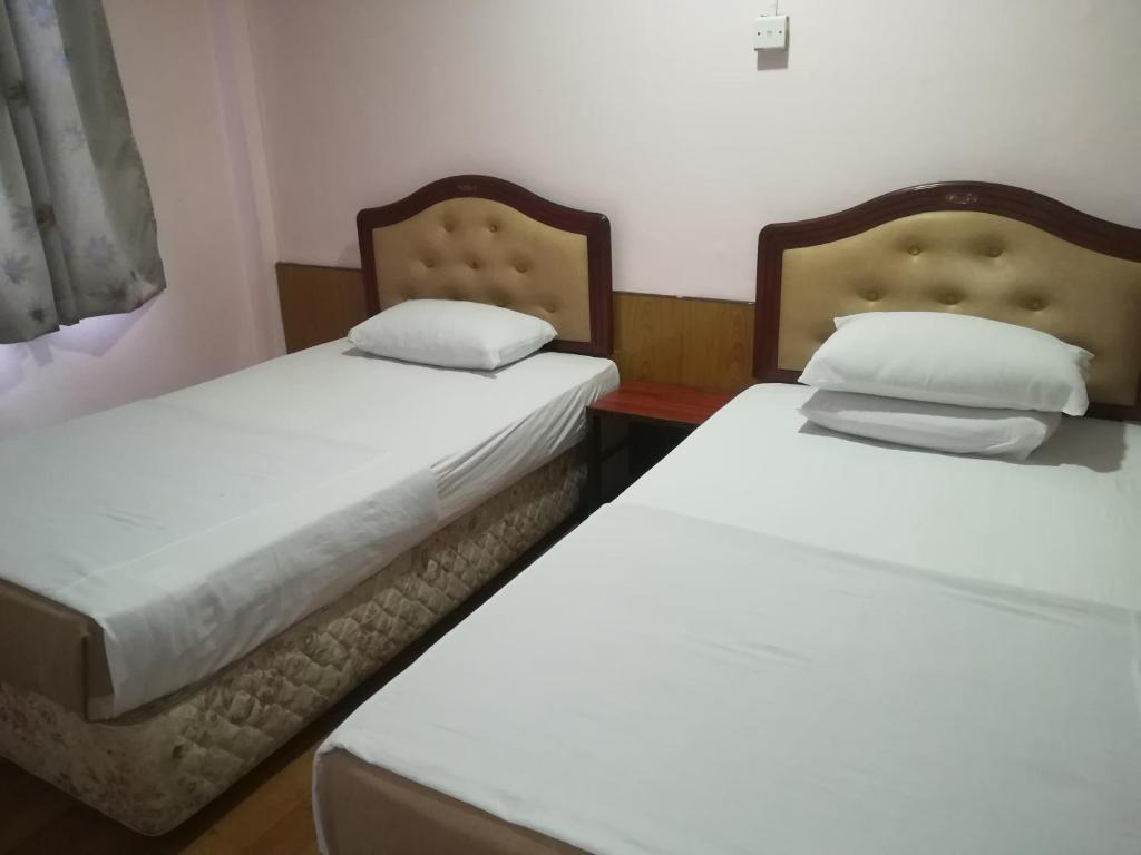 诗巫MIRAMAR HOTEL的两张睡床彼此相邻,位于一个房间里