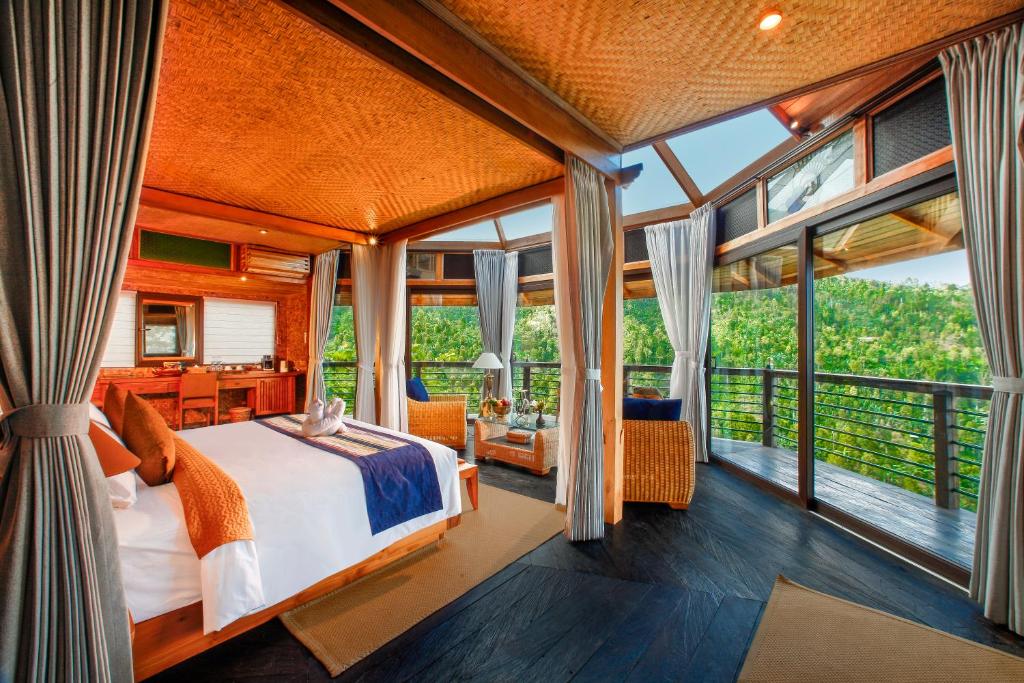 姆杜克Munduk Heaven Luxury Villas的一间设有床铺的卧室,位于带窗户的房间内