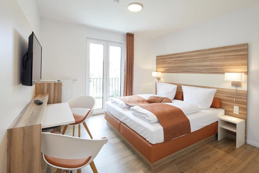 NeuensteinVR-Serviced Apartments Obergeis的酒店客房配有一张床、一张桌子和一把椅子。