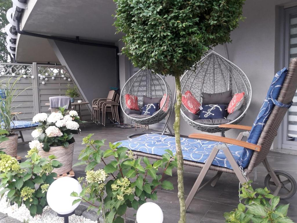 波别罗沃Apartament Bursztyn的庭院设有两把藤椅和一棵树