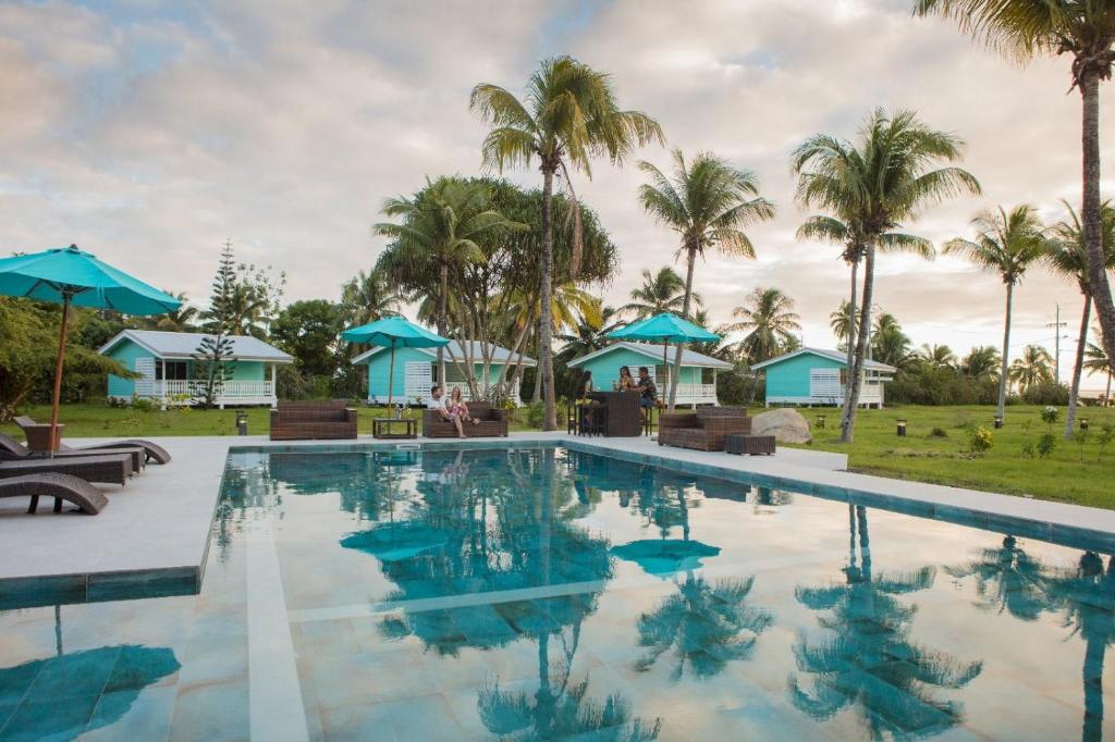 乌图罗阿Raiatea Lodge Hotel的一座棕榈树和别墅的游泳池