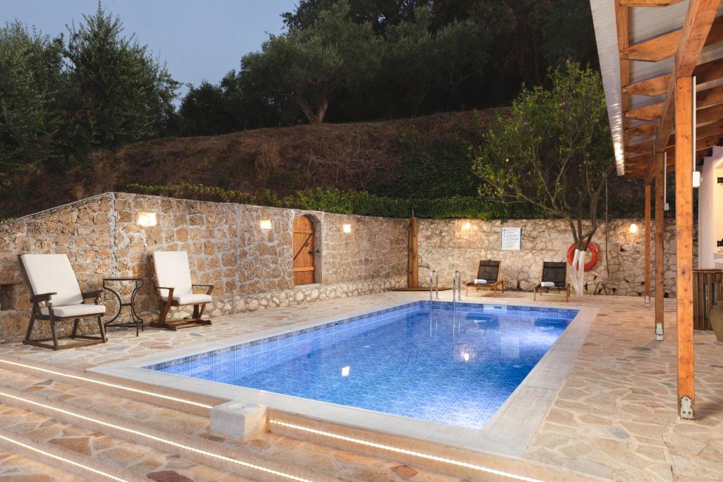 阿凯松Villa Rocale的庭院内的游泳池,配有椅子和石墙