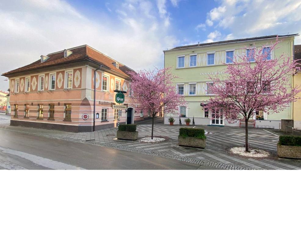 巴特哈尔Gasthof Hametner mit Innviertlerhof mit direktem Zugang zur Therme Mediterrana durch unseren Garten!的街道前方有粉红色树木的建筑