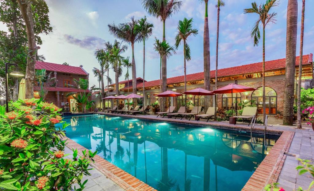 宁平Tam Coc Banana Bungalow的棕榈树和遮阳伞的酒店游泳池