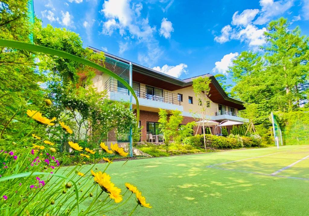 轻井泽IKOI Villa的一座带网球场和鲜花的房子