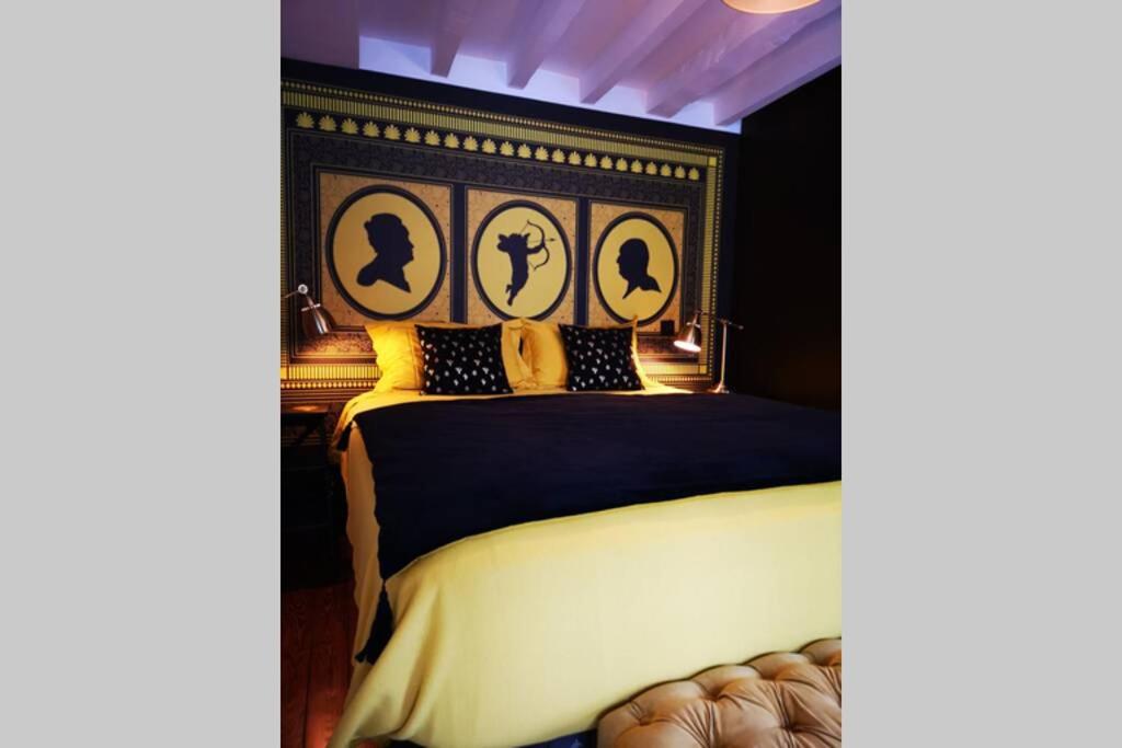 里昂Le Boudoir的一间卧室配有一张带黑色和金色床头板的床