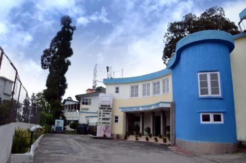 大吉岭Darjeeling Tourist Lodge的前面有棵树的蓝色建筑