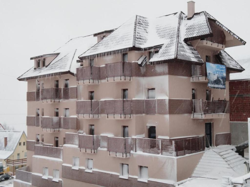 科帕奥尼克Belvedere Hills Luxury Apartments and Spa的一座有雪盖屋顶的建筑