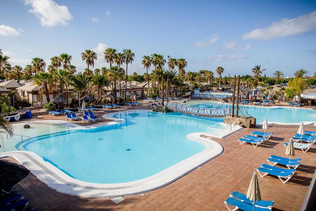 马斯帕洛马斯Caybeach Princess的一个带蓝色椅子和棕榈树的大型游泳池