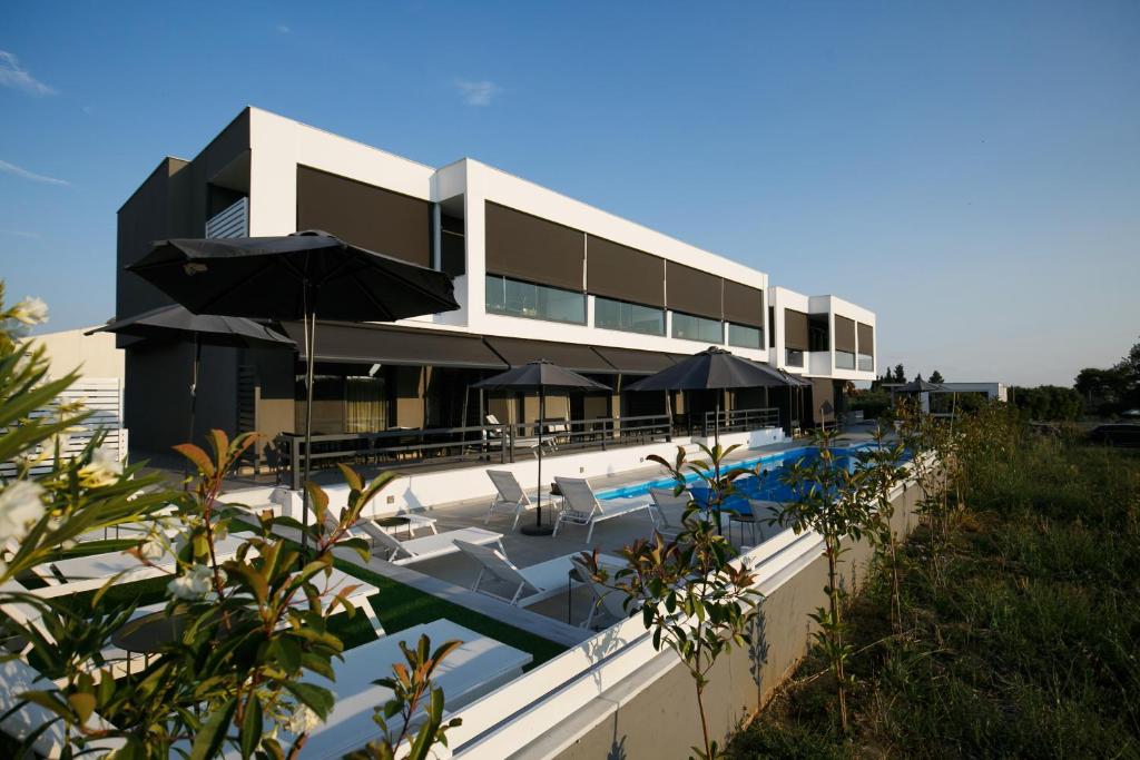 耶拉基尼ISALOS GERAKiNi的一座带游泳池的建筑,配有遮阳伞
