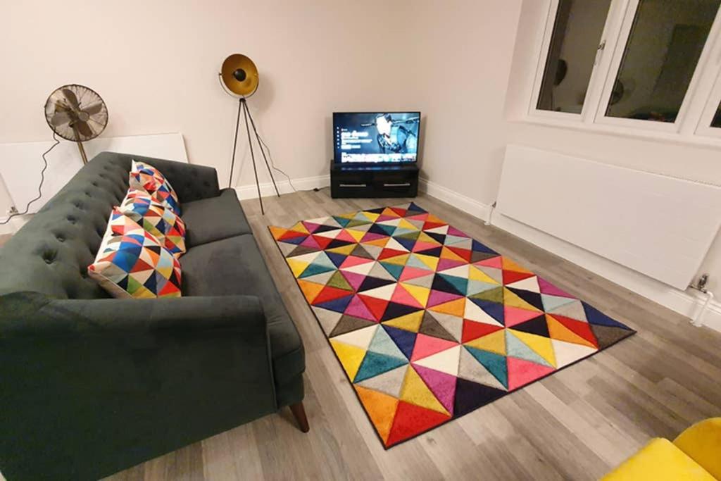 布伦特伍德Garland Modern Spacious Apartment, Brentwood 2的客厅配有沙发和色彩缤纷的地毯