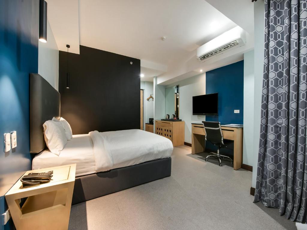 马尼拉Bay Area Suites Manila的酒店客房配有一张床、一张书桌和一台电视。