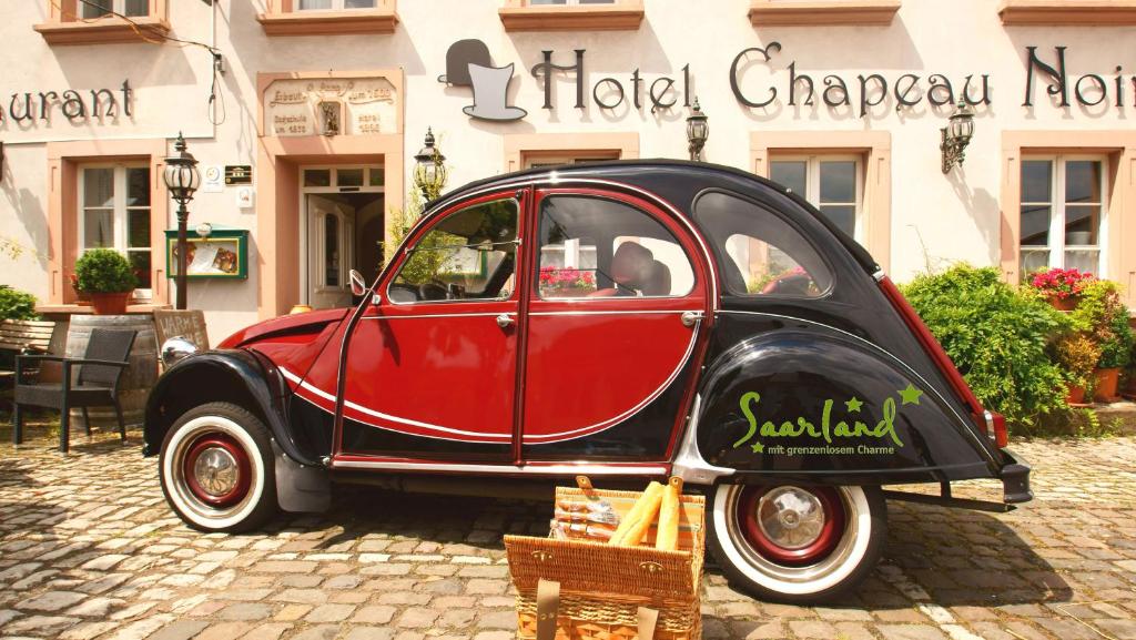 ÜberherrnUNO Hotel Chapeau Noir的停在大楼前的一辆红色和黑色的汽车