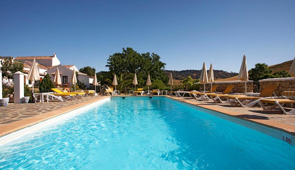 隆达科蒂乔拉斯皮莱塔斯酒店的一个带椅子和遮阳伞的大型游泳池