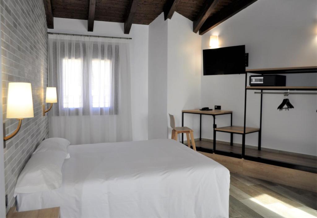 布里韦加Hostal Restaurante Villa de Brihuega的白色的卧室配有白色的床和电视。