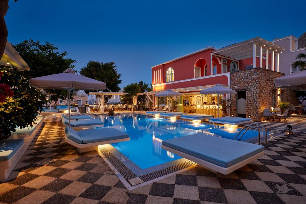 卡马利蓝色海洋酒店的一座带躺椅和遮阳伞的游泳池位于一座大楼旁