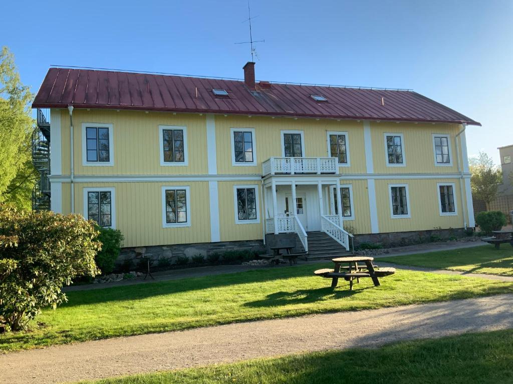 韦克舍Evedals Vandrarhem Växjö的黄色的房子,前面设有野餐桌