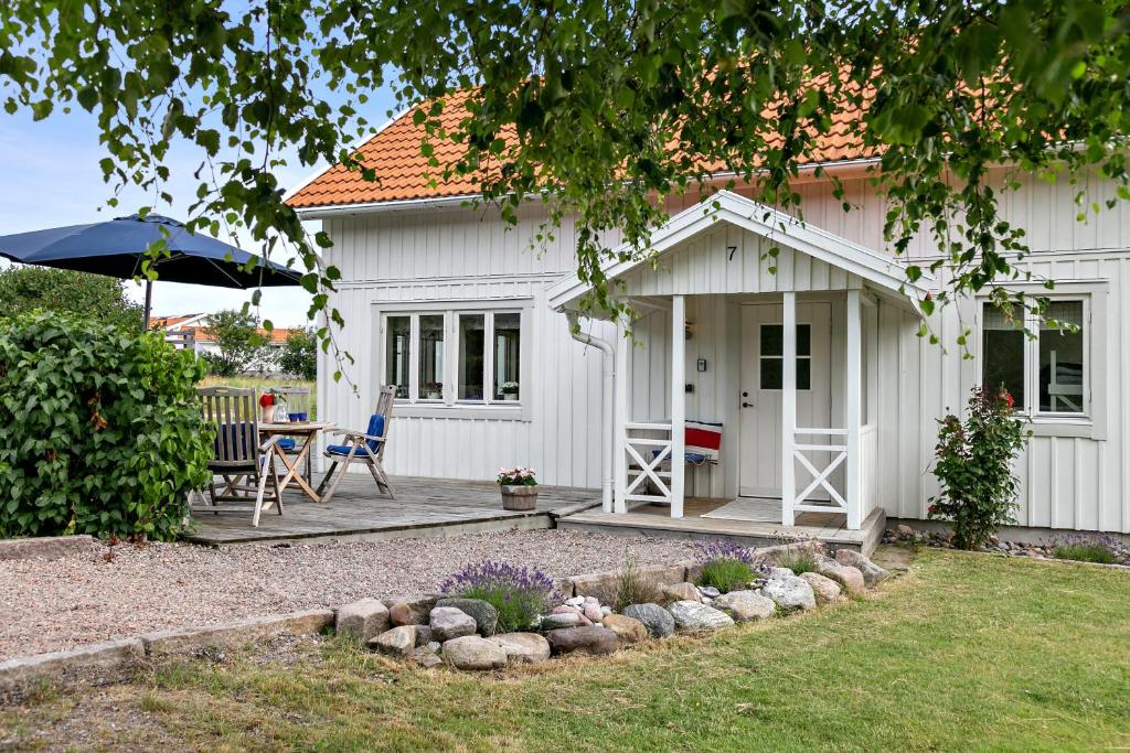 格雷伯斯塔德Villa Tjurpannan Grebbestad的白色的房子,配有桌椅和遮阳伞