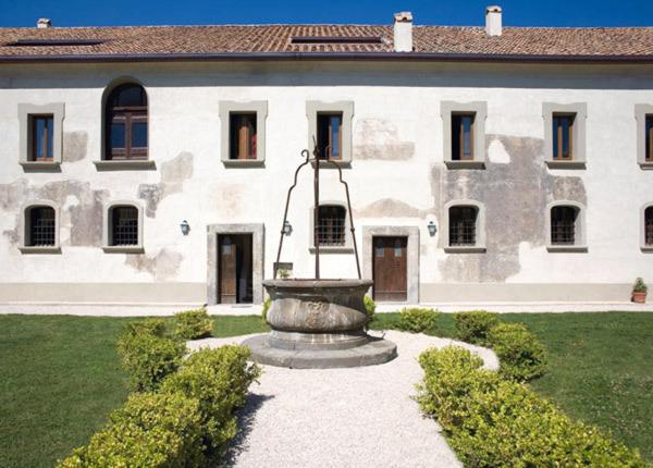 维克艾库塞Relais Villa Giusso的一座大型白色建筑,在庭院里设有一个喷泉