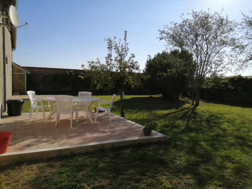 圣马塞尔Gîte de la Bigaillonne的庭院设有白色的椅子和桌子。