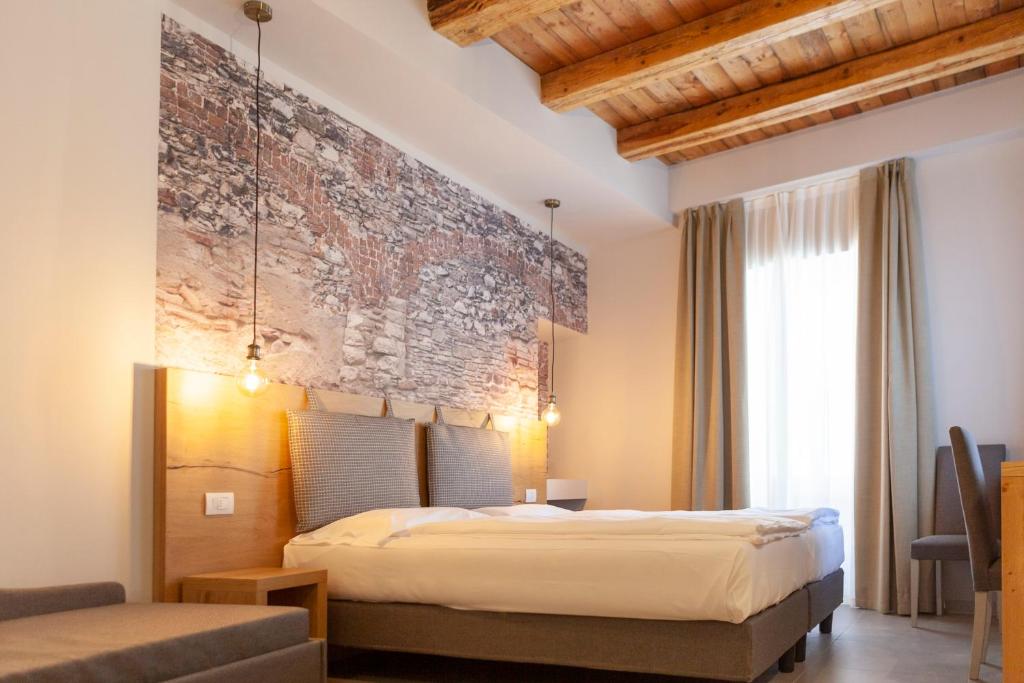 托尔博莱epOche Hotel Zanella 1889的一间卧室设有一张床和石墙