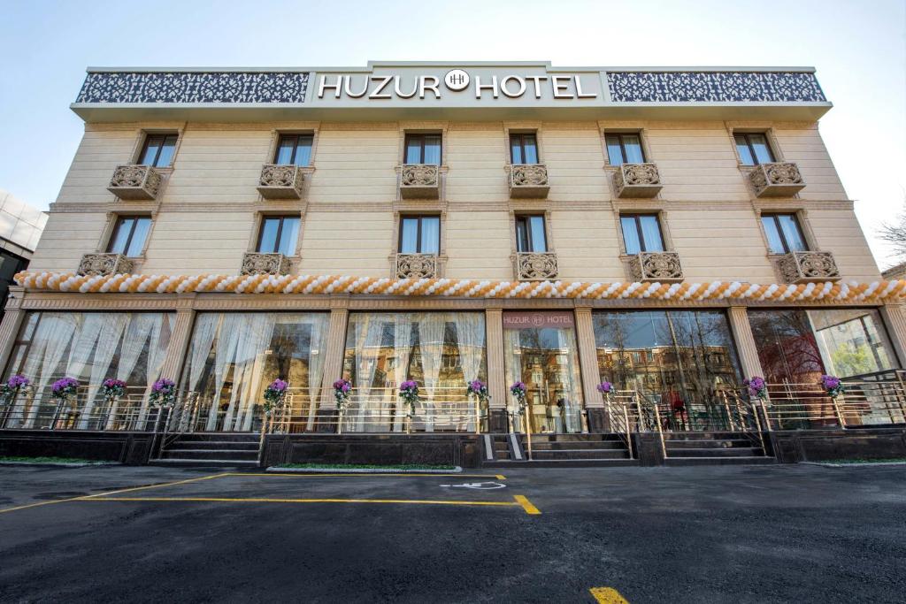 塔什干Huzur Hotel Tashkent的一座酒店大楼,前面有标志