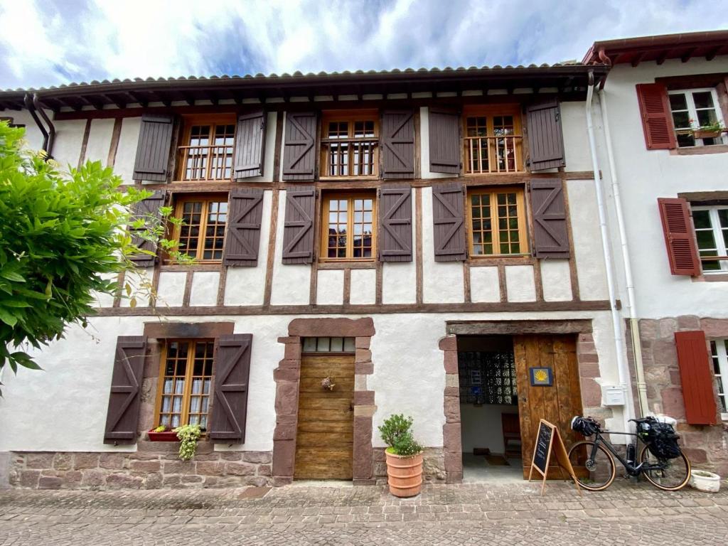 圣让皮耶德波尔Gite de la Porte Saint Jacques: a hostel for pilgrims的一座带窗户的老房子,前面有一辆自行车
