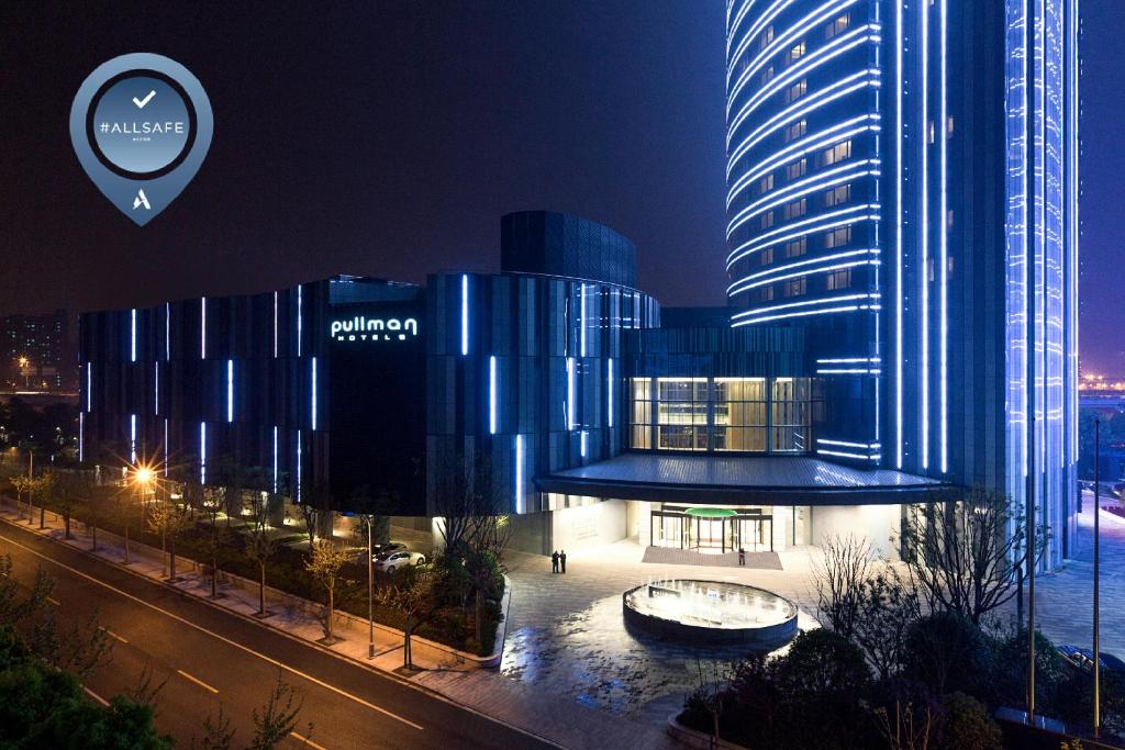 上海上海中星铂尔曼大酒店的一座蓝色的大建筑,晚上有一座建筑