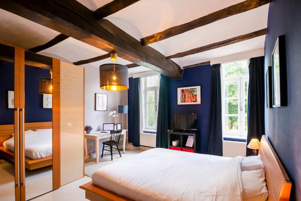 蒙斯金佩蒂特龙旅馆的一间卧室设有蓝色的墙壁、一张床和一张书桌