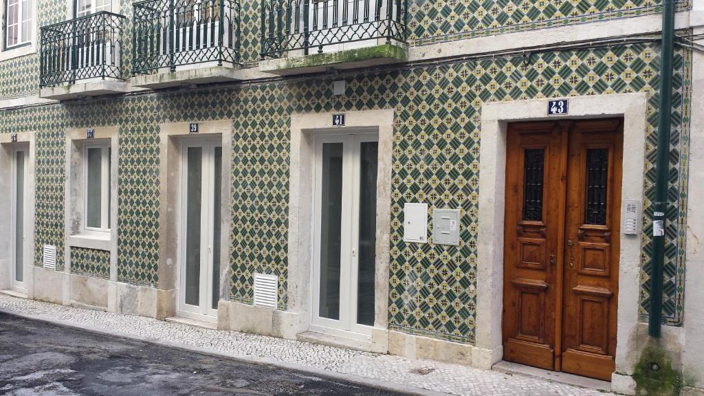 里斯本罗西奥套房酒店的一座拥有绿色和白色瓷砖的建筑,设有木门