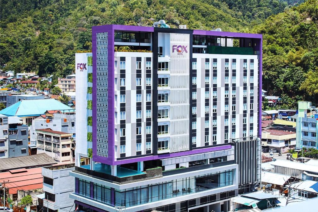 查亚普拉Fox Hotel Jayapura的城市中一座高大的紫色和白色建筑
