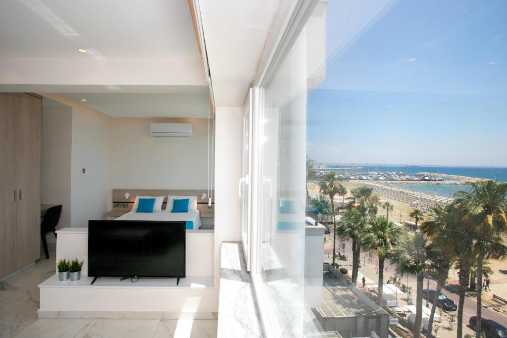 拉纳卡Les Palmiers Sunorama Beach Apartments的一间配有电视的客厅,享有海滩美景