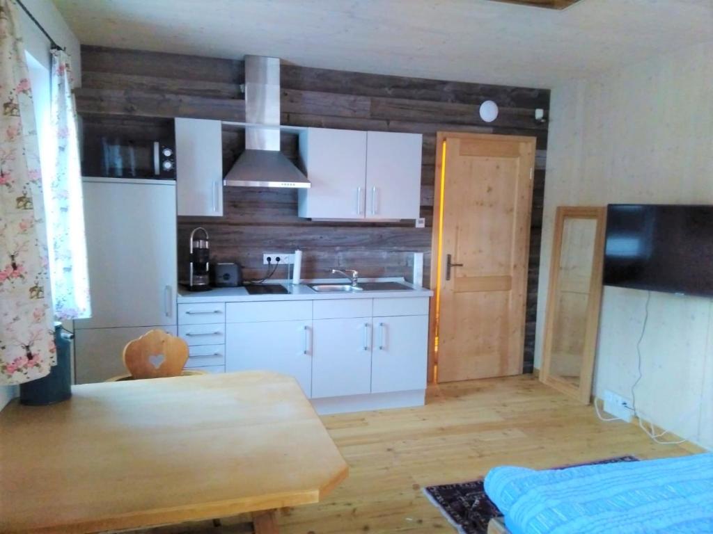 隆高地区圣玛格丽滕Country Appartement Lungau的厨房配有白色橱柜和木桌