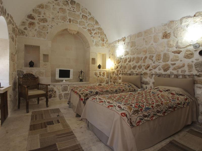 Midyat卡斯诺罗斯酒店的一间卧室设有两张床和石墙