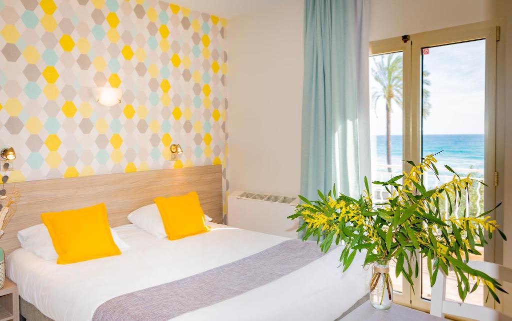 罗克布吕讷-卡普马丹Hotel et Appartements Reine D'Azur的一间卧室配有一张带黄色枕头的床和一扇窗户