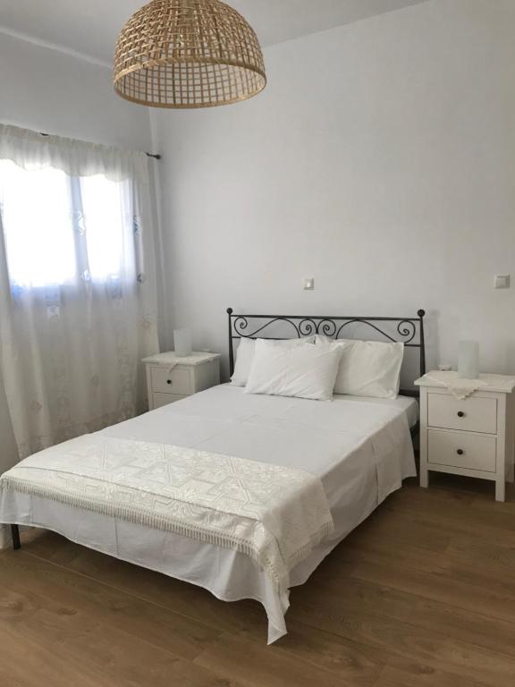 佐努萨岛Vegera Apartment 'Sofrano', Stavros Donoussa的一间卧室配有一张带白色床单和吊灯的床。