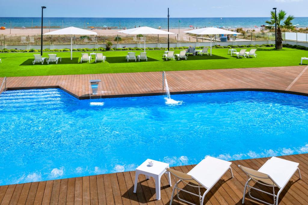卡斯特尔德费尔斯普拉亚费尔斯酒店的一个带椅子和遮阳伞的游泳池和海滩