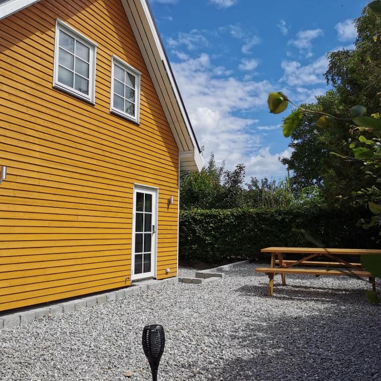 TranebjergSamsø værelseudlejning的旁边设有长凳的黄色建筑