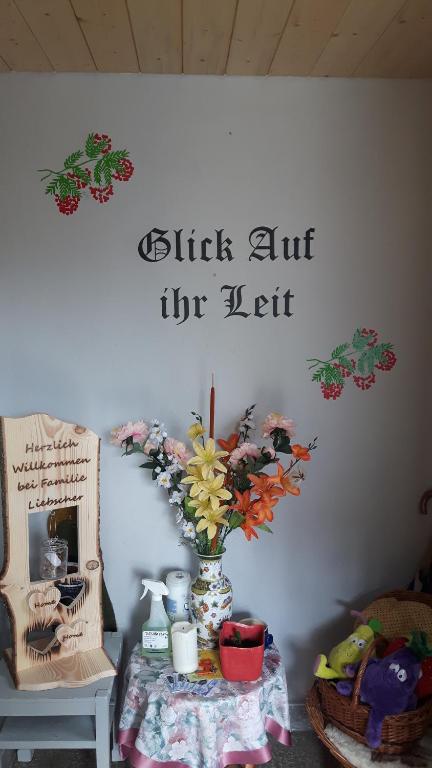SehmatalFerienwohnung Liebscher的墙上有标牌的花瓶桌子