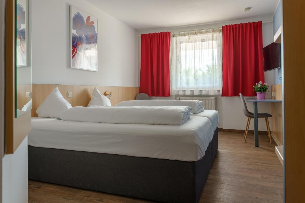 HeimsheimMotel Drei König- Ihr Transithotel的配有红色窗帘的酒店客房的两张床